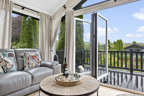 Ein modernes Wohnzimmer mit einer Ledersofa, einem runden Couchtisch und einer großen Glasschiebetür, die auf einen Balkon führt.