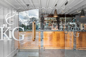 A bar area with a wooden counter, copper fixtures, and a glass wall offering a view of the outdoors. - Brayford Lodge, Kentisbury Grange -  Free WiFI & Parking - Hot Tub - Pets (Barnstaple)