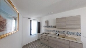 A kitchen with wooden cabinets, a tiled backsplash, and a window with a curtain. - Lovely guesthouse 10 minutes from the beautiful beaches of the Gulf of Orosei (Irgoli)