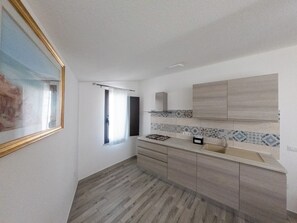 Eine Küche mit Holzausstattung, einer Fliesenküchenwand und einem Fenster mit Vorhang.
