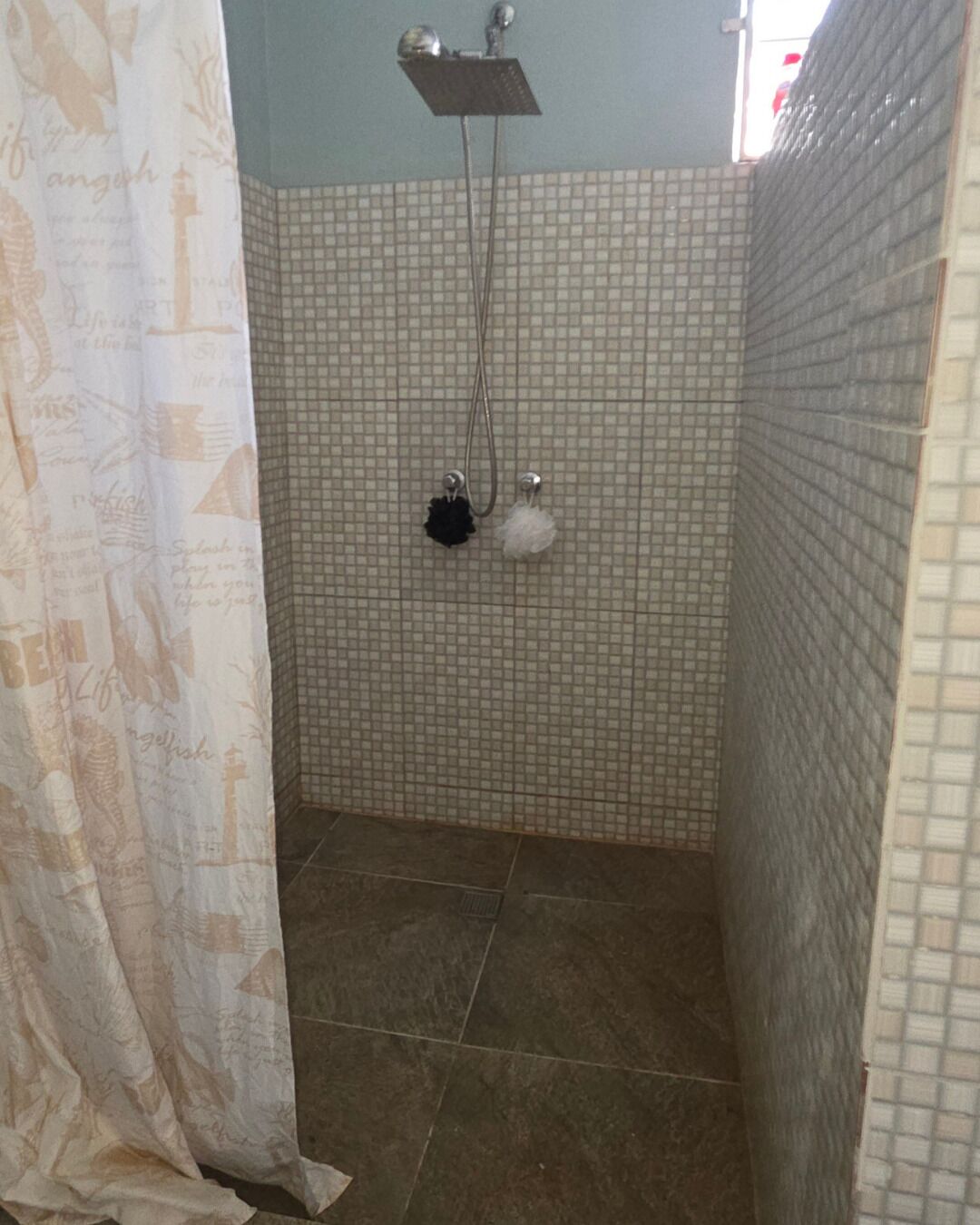 A bathroom with a shower, tiled walls, and a curtain.