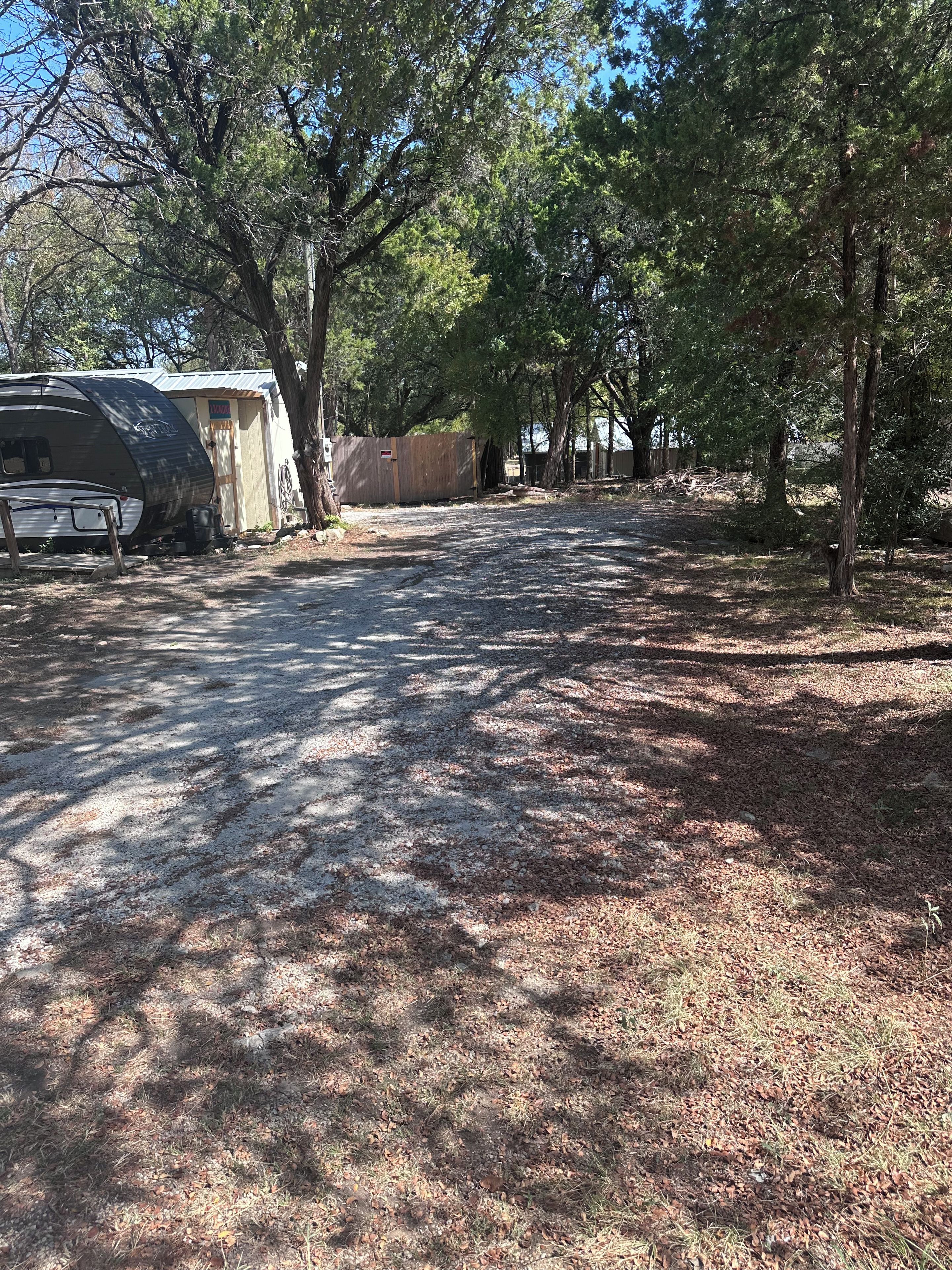 Ein Campingplatz mit Reisemobilen, Bäumen und einem Kiesweg.