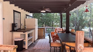 An outdoor patio with a wooden table, chairs, a refrigerator, and a coffee maker. - The Fishin’ Shack, on Lake whitney. (Clifton)