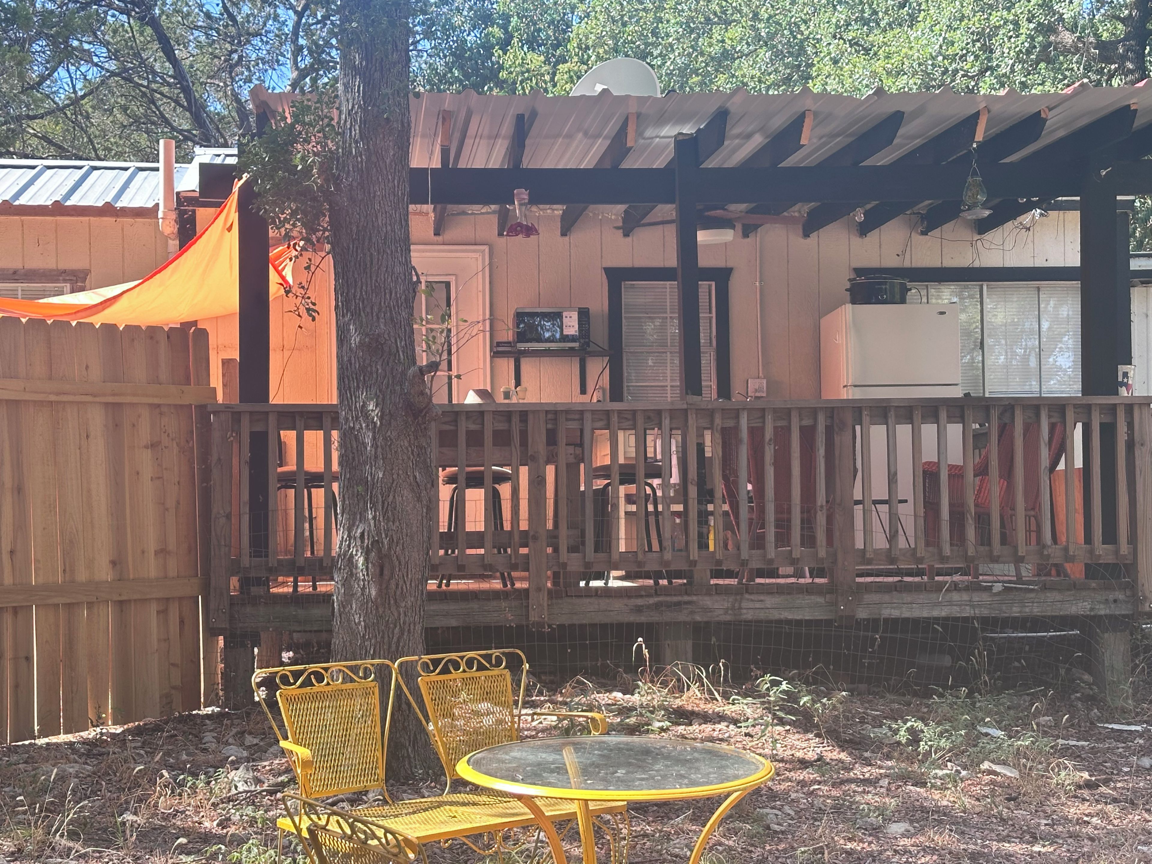 Un espace extérieur clos, agrémenté d’une pergola en bois, d’une table et de deux chaises.