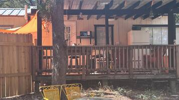 Un'area esterna recintata con una pergola in legno, un tavolo e due sedie.