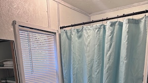 A bathroom with a toilet, sink, and shower curtain. - The Fishin’ Shack, on Lake whitney. (Clifton)