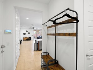 Ein Hotelzimmer mit Küchenzeile, einer Holzbank, einem Kleiderständer und einem an der Wand montierten Fernseher.