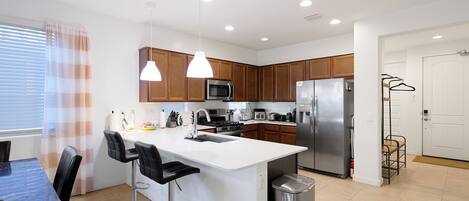 A modern kitchen with a central island, stainless steel appliances, and pendant lighting.