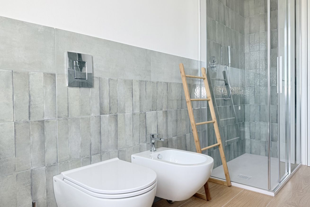 Ein modernes Badezimmer mit Toilette, Bidet und einer Duschkabine aus Glas.
