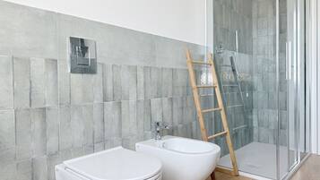 Ein modernes Badezimmer mit Toilette, Bidet und einer Duschkabine aus Glas.