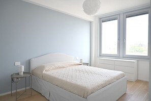 Een slaapkamer met een bed, nachtkastjes, een raam en een plafondlamp.