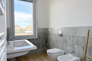 Ein Badezimmer mit Fenster, Waschbecken, Toilette und Bidet.