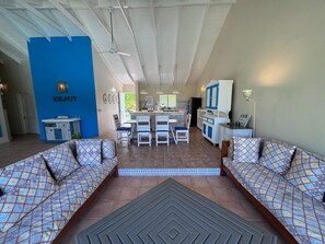 A spacious living area with a dining table and chairs, a kitchen in the background, and a blue accent wall. - Spacious 3-bedroom condo in adorable Las Terrenas with AC (Las Terrenas)