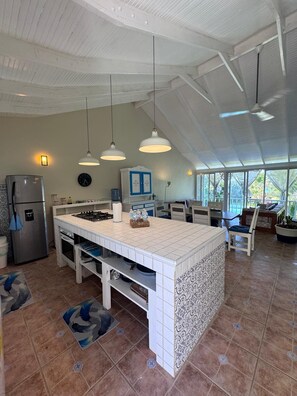 A spacious kitchen with a large island, pendant lights, a refrigerator, and a dining area with chairs and a table. - Spacious 3-bedroom condo in adorable Las Terrenas with AC (Las Terrenas)