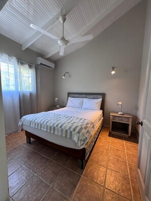 A bedroom with a bed, ceiling fan, air conditioning unit, bedside lamps, and a nightstand. - Spacious 3-bedroom condo in adorable Las Terrenas with AC (Las Terrenas)