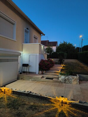 Il s’agit d’une propriété résidentielle dotée d’un garage, d’un petit espace extérieur aménagé pour s’asseoir et d’un chemin bien éclairé.
