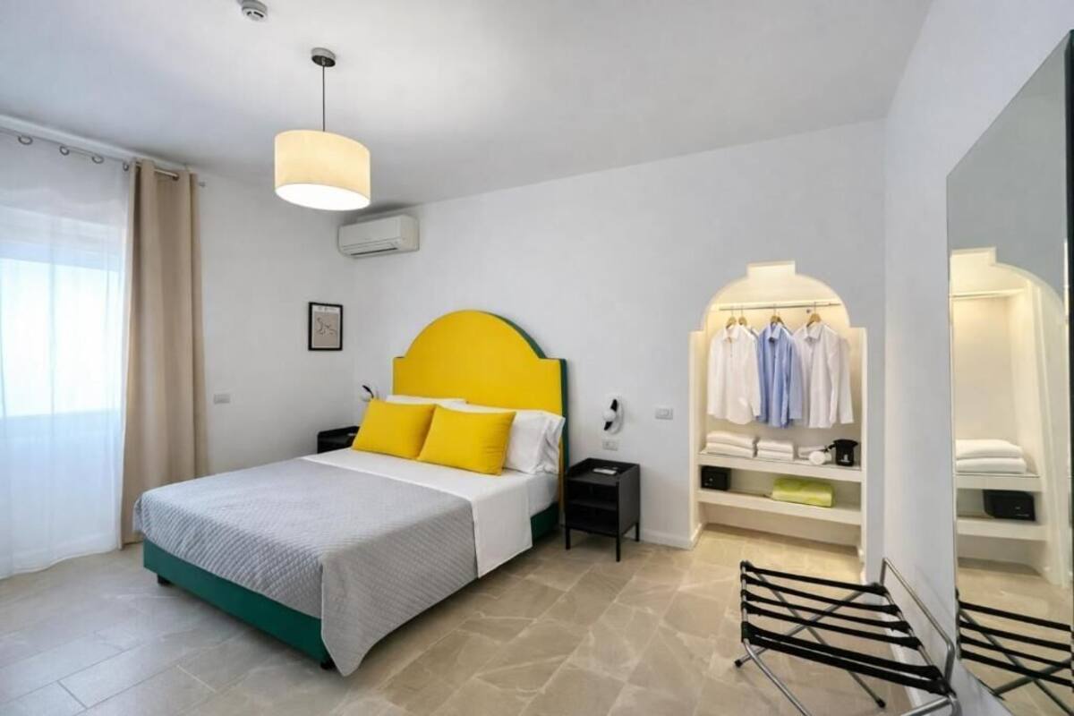 A bedroom with a bed, a nightstand, a hanging light fixture, a wardrobe, and a mirror.