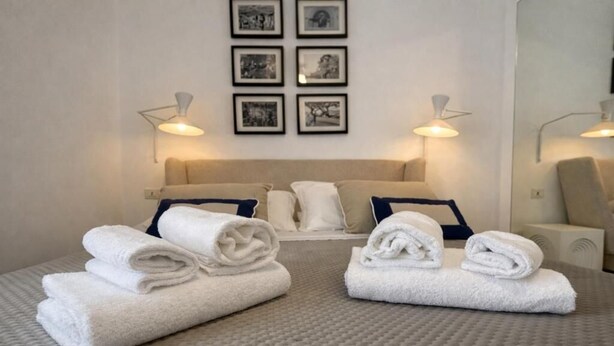 Habitación de hotel con una cama, dos mesitas de noche, un cabecero y cuadros en la pared.