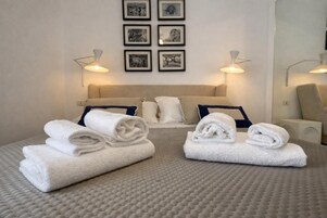 A hotel room with a bed, two side tables, a headboard, and framed pictures on the wall.