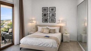 Un dormitorio con cama, un balcón con mobiliario exterior y cuadros en la pared.