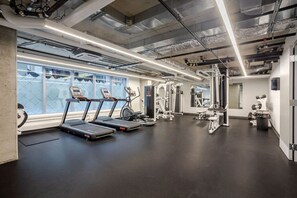 Un gimnasio con cintas de correr, máquinas de pesas y un ventanal grande.