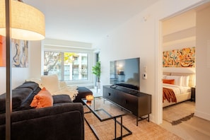 Una sala de estar moderna con un sofá, televisor y una mesa de centro de vidrio.