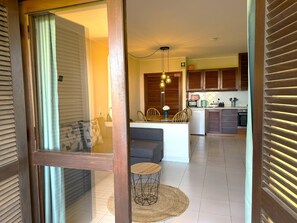 A modern kitchen with wooden cabinets, a dining area with a round table and chairs, and a visible medical emergency sign. - Authentic apartment, 2 lovely private balconies (Albufeira)
