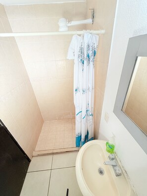 Ein Badezimmer mit Dusche, Waschbecken und Spiegel.