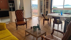 Een woonkamer met een bank, stoelen, een salontafel, een eettafel en uitzicht op de omgeving.