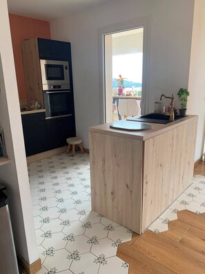 A compact kitchen with a central island, a microwave, and an oven. - Family apartment with sea view 500m from the sea (Albitreccia)