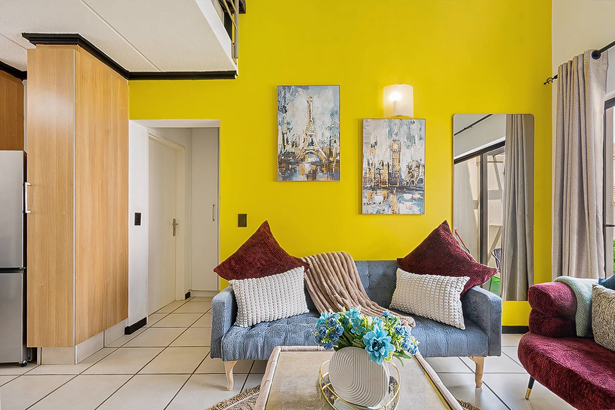 A living room with a yellow wall, a sofa, a coffee table, and a door leading to another room.