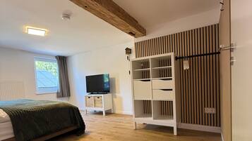 Ein Schlafzimmer mit Bett, Fernseher, Kleiderschrank und einem Fenster mit Vorhängen.