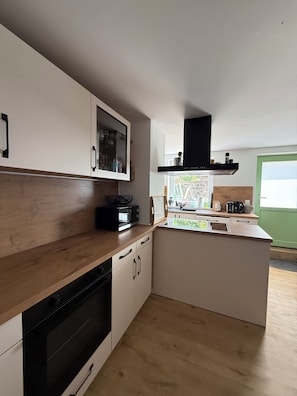 Eine moderne Küche mit Einbauofen, Mikrowelle und einem großen Fenster.