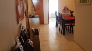 A dining area with a table set for four, a refrigerator, and a door leading to another room. - Delgado Airport Suite (Lisbon)