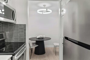 Eine moderne Küche mit Mikrowelle, Herd und Kühlschrank, einem runden Tisch mit Stühlen und einer Pendelleuchte.
