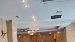 A reception area with a sofa, two chairs, a small table, a chandelier, a welcome sign, and a wall with clocks. - Grand Memphis & Roof Top Restaurant (Luxor)