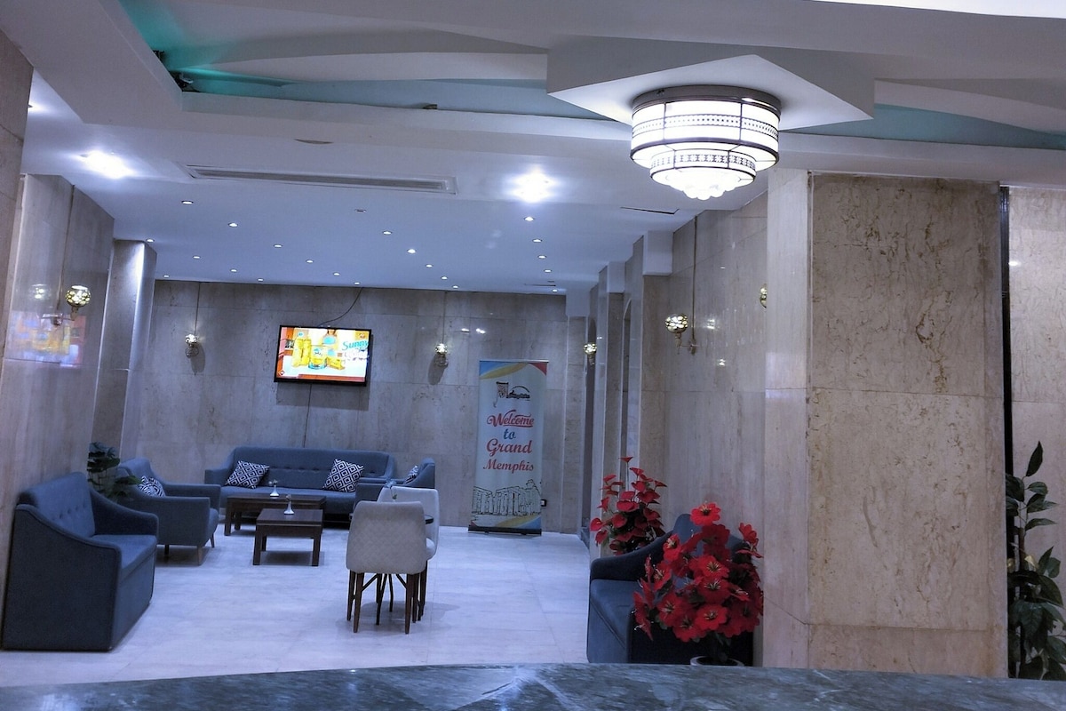 A lobby with a reception desk, seating area, and a television screen.