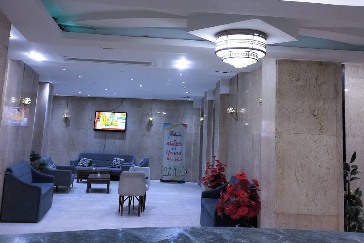 A lobby with a reception desk, seating area, and a television screen.