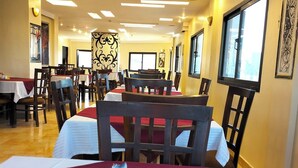 A restaurant with tables and chairs, an exit sign, and a window. - Grand Memphis & Roof Top Restaurant (Luxor)