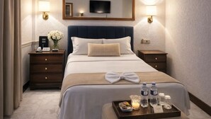 A hotel room with a large bed, bedside tables, a TV, and a tray with toiletries. - Grand Memphis & Roof Top Restaurant (Luxor)