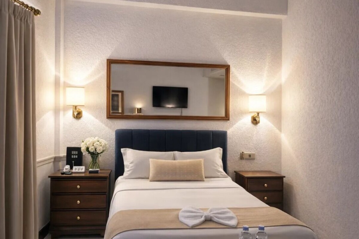 A hotel room with a large bed, bedside tables, a TV, and a tray with toiletries.