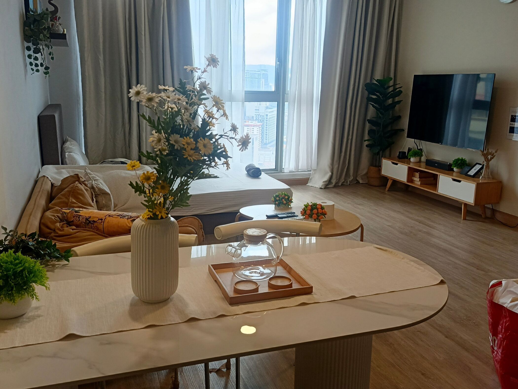 A modern living room with a sofa, a coffee table, a TV, and a large window with curtains.