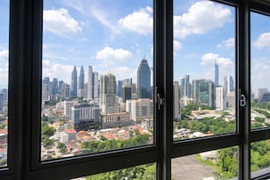 Stadtbild durch ein Fenster mit Blick auf Hochhäuser und einen klaren Himmel.