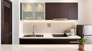 A modern kitchen with dark cabinets, a stainless steel sink, and a built-in stove. - Regalia Sky Pool KLCC Luxury KL by SS (Kuala Lumpur)