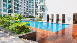 Ein modernes Hotel mit Schwimmbad, Holzterrasse und üppiger Bepflanzung.
