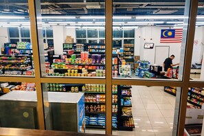 A grocery store interior with shelves stocked with various products, a cashier at the counter, and a Malaysian flag on the wall. - Regalia Sky Pool KLCC Luxury KL by SS (Kuala Lumpur)