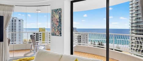 A balcony with a view of the ocean and a building across the water.