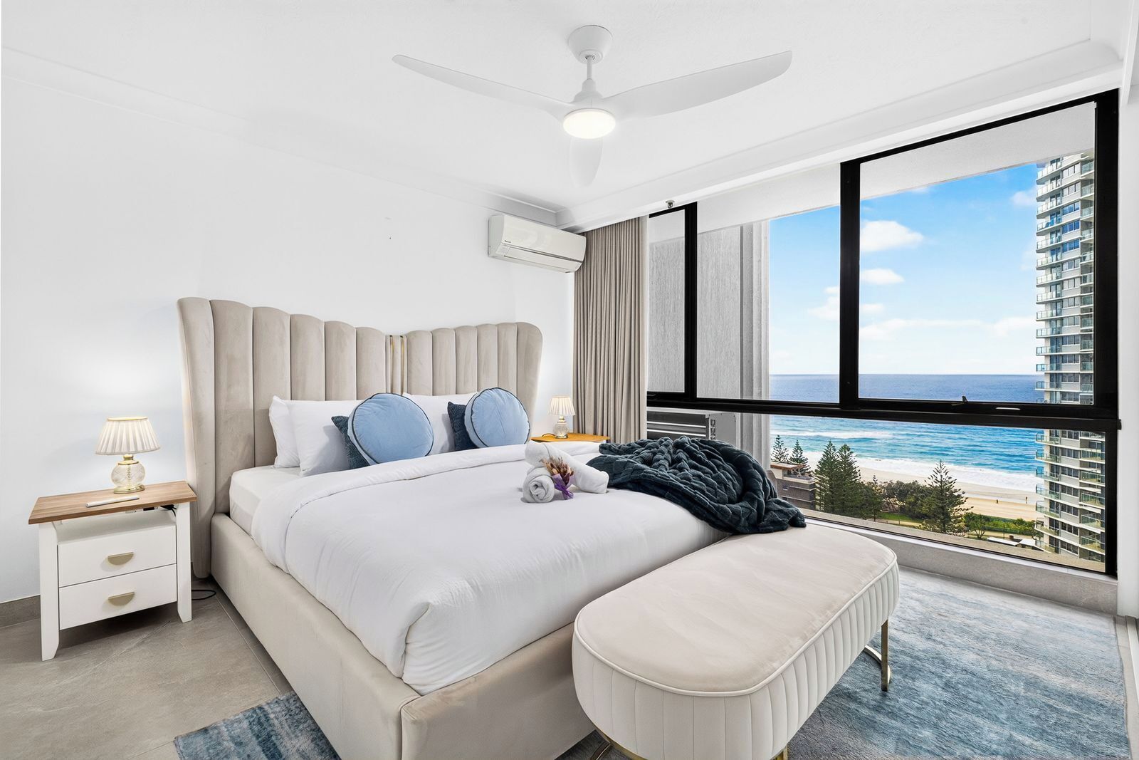 Habitación de hotel con una cama grande, ventilador de techo, vista al océano y un balcón.