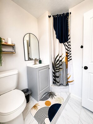 Une salle de bain équipée de toilettes, d’un lavabo, d’un miroir et d’un rideau de douche.