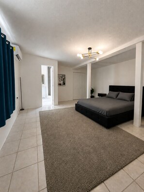 A bedroom with a bed, a rug, a nightstand, a lamp, and a ceiling light fixture.